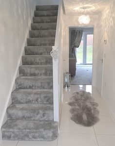 there is a carpet on the floor in front of the stairs that lead up to the second floor