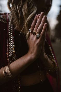 a woman with her hands folded in prayer and wearing gold jewelry on her left hand