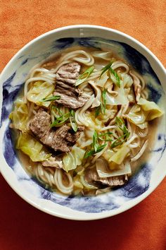 a bowl filled with noodles and meat on top of a table