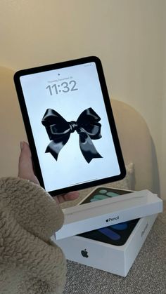 a person holding an ipad with a black bow on it