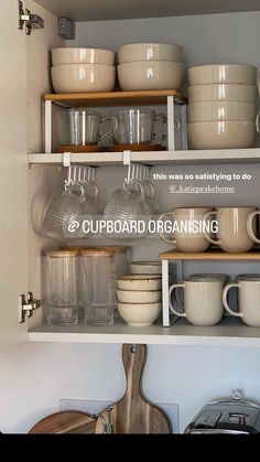 an open cupboard filled with dishes and cups