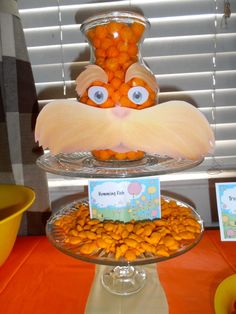 there is a cake that looks like an orange fish on top of a plate with candy