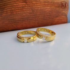 two yellow gold wedding rings with diamonds on the top and bottom, sitting next to each other