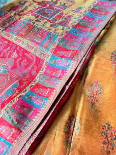 an orange, pink and blue sari is laying on top of the other fabric