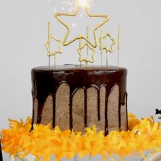 a birthday cake with chocolate icing and stars on top, surrounded by yellow flowers