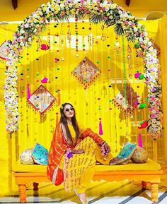 a woman sitting on top of a bench in front of a yellow stage with decorations