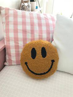 a smiley face pillow sitting on top of a bed