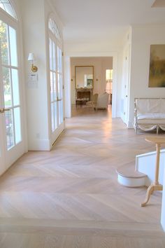 an empty hallway with white furniture and large windows on both sides, leading to the dining room