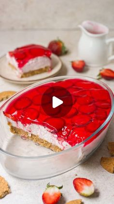 a strawberry cheesecake in a glass dish on a table with crackers and strawberries