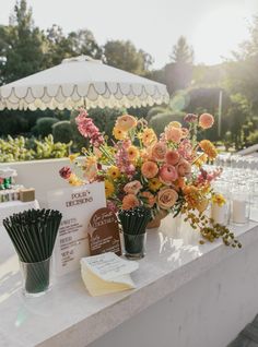 flowers in vases are sitting on a table at an outdoor wedding reception with cards and place settings