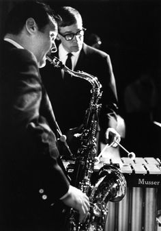 two men in suits are playing saxophone together