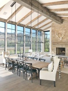 a dining room table and chairs in front of large windows with wooden beams on the ceiling