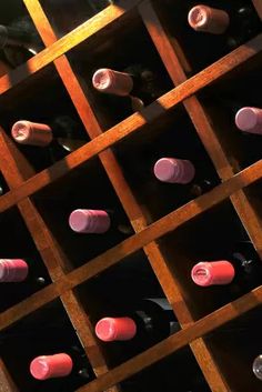 several rows of wine bottles are lined up in a wooden case on the side of a wall