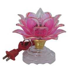 a pink flower sitting on top of a glass vase next to a red power cord