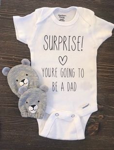 two teddy bears sitting next to each other on top of a wooden table with a shirt that says surprise you're going to be a dad