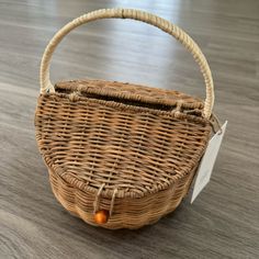 a small wicker basket with a tag on the handle sits on a wooden floor