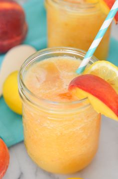 two mason jars filled with orange juice and topped with an apple, lemon and blue striped straw