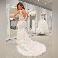 a woman standing in front of a mirror wearing a wedding dress with ruffles on it