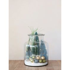 a glass jar filled with ornaments on top of a wooden table