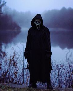 a person in a hooded costume standing by the water