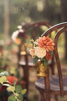 an arrangement of flowers is placed in a vase on the back of a wooden chair