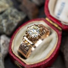 an engagement ring in a red velvet box with stones around it and a diamond on the side