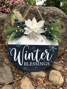 a wooden sign that says winter blessing on the side of a rock in front of some rocks