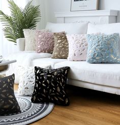 a living room filled with lots of pillows on top of a white couch next to a potted plant