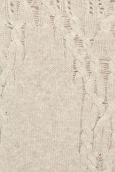 closeup of the textured knit fabric on a white sweater, with an intricate lace pattern