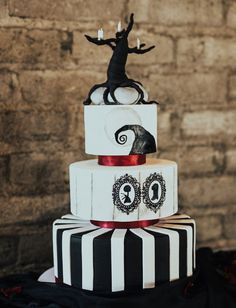 a three tiered cake decorated with black and white striped icing, topped with a figurine on top