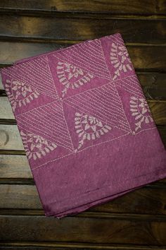 a purple cloth with white designs sitting on top of a wooden table next to a pair of scissors