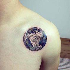 a man's chest with a small globe tattoo on the left side of his shoulder