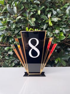 a black and gold trophy with the number 8 on it's side, in front of a bush