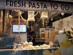 a store window with pasta hanging from it's sides and the words fresh pasta to go written in large letters