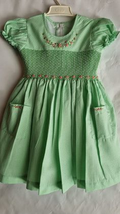 "This dress is smocked with matching green color and beautiful hand embroidered roses added around the neckline and on the smocking. The skirt comes with matching pockets, with same detailed hand embroidered roses.   Dress is fully lined with matching soft cotton material. The back closes with a zip and tie sashes. Material Outer fabric - Polycotton Inner fabric -100% Cotton  Instructions Cold gentle hand wash Available sizes, Size 3-6 months (AU 00) Length 14\" Chest circumference 20\" Size 6-12 months (AU 0) Length 16\" Chest circumference 21\" Size 1  (12-18 months) Length 18\" Chest circumference 22\" Size 2 (18-24 months) Length 20\" Chest circumference 23\" Size 3 Length 22\"  Chest circumference 24\" Size 4  Length 24\"  Chest circumference 25\" Size 5   Length 26\"  Chest circumfer Short Sleeve Gingham Smocked Dress, Gingham Short Sleeve Dress With Smocked Bodice, Short Sleeve Gingham Dress With Smocked Bodice, Gingham Dress With Smocked Bodice And Short Sleeves, Fitted Gingham Smocked Dress With Short Sleeves, Short Sleeve Gingham Smock Dress, Gingham Cotton Smocked Dress With Short Sleeves, Cute Cotton Smocked Dress, Cute Cotton Smocked Dress In Gingham