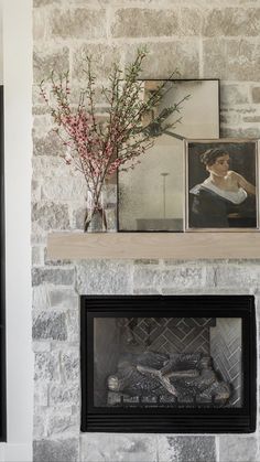 a fireplace with pictures on the mantle and a vase filled with flowers next to it