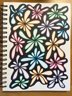 a spiral notebook with an image of flowers on the front and back cover in black, pink, blue, green, yellow