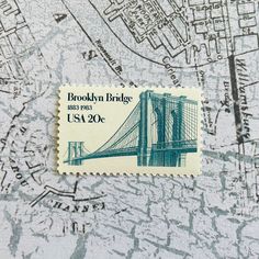 a postage stamp on top of a map with the brooklyn bridge in blue and white