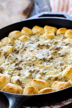 a casserole dish with cheese and meat in it sitting on a wooden table