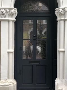 a black front door with two glass panes on the top and bottom, surrounded by white pillars