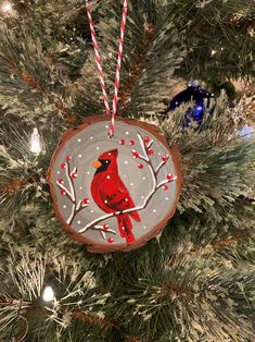 a wooden ornament with a cardinal painted on it hanging from a christmas tree