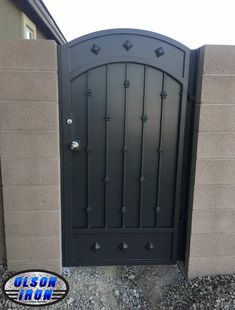 an iron gate is shown in front of a stone wall and concrete block walls, with the door open