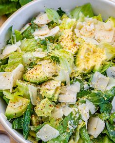 a white bowl filled with lettuce, cheese and other toppings on top of a wooden table