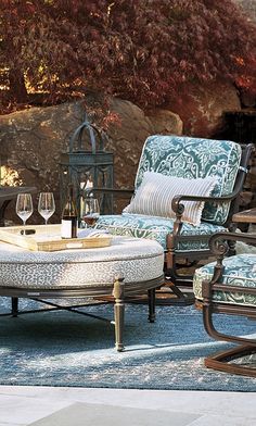 an outdoor patio furniture set with wine glasses on the table and two chairs in front of it