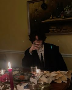 a person sitting at a table with candles in front of them and papers on the table