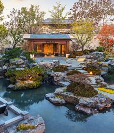 an outdoor garden with rocks and trees in the foreground, surrounded by water features