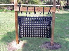 a wooden rack with several knives hanging from it's sides in the grass next to a fence