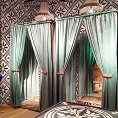 two green curtains are hanging in front of a mirror with an intricate design on it