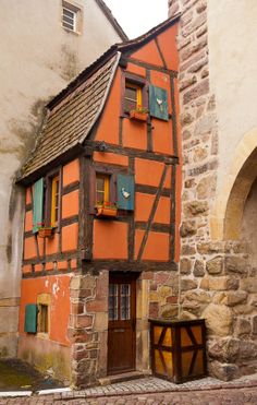 an orange and brown house sitting next to a building with two doors on each side