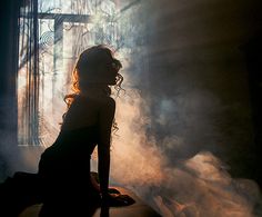 a woman sitting on a chair in front of a window with steam coming out of it